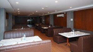 A modern restaurant with booths and tables, wooden paneling, and recessed lighting. - Hotel Orcella (Tirupati)