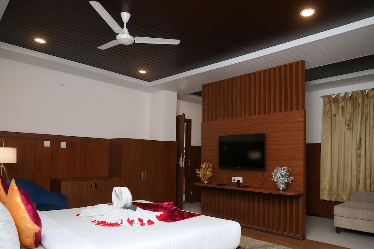 A modern bedroom with a wooden bed, a ceiling fan, a flat-screen TV, and a wooden wardrobe.