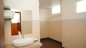 A small bathroom with a white sink, a mirror, and a towel rack. - Hotel Orcella (Tirupati)