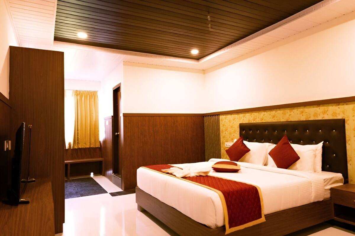 A hotel room with a large bed, wooden headboard, and a small bedside table.