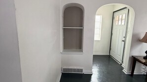 A hallway with white walls, a dark floor, and a door with windows. - Home Near Toll Road/BP/Hospitals 2 Bedroom (Gary)