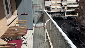 A balcony with a table and chairs, a refrigerator, and a view of a multi-story building with balconies. - Domus Livia Vatican Cipro metro station (Roma)