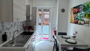 A modern kitchen with a central island, a dining area with a table and chairs, and a view through an open door to an outdoor balcony. - Domus Livia Vatican Cipro metro station (Roma)