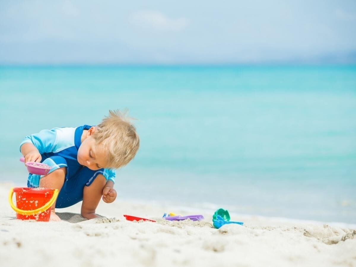 Un niño jugando con arena en la playa.