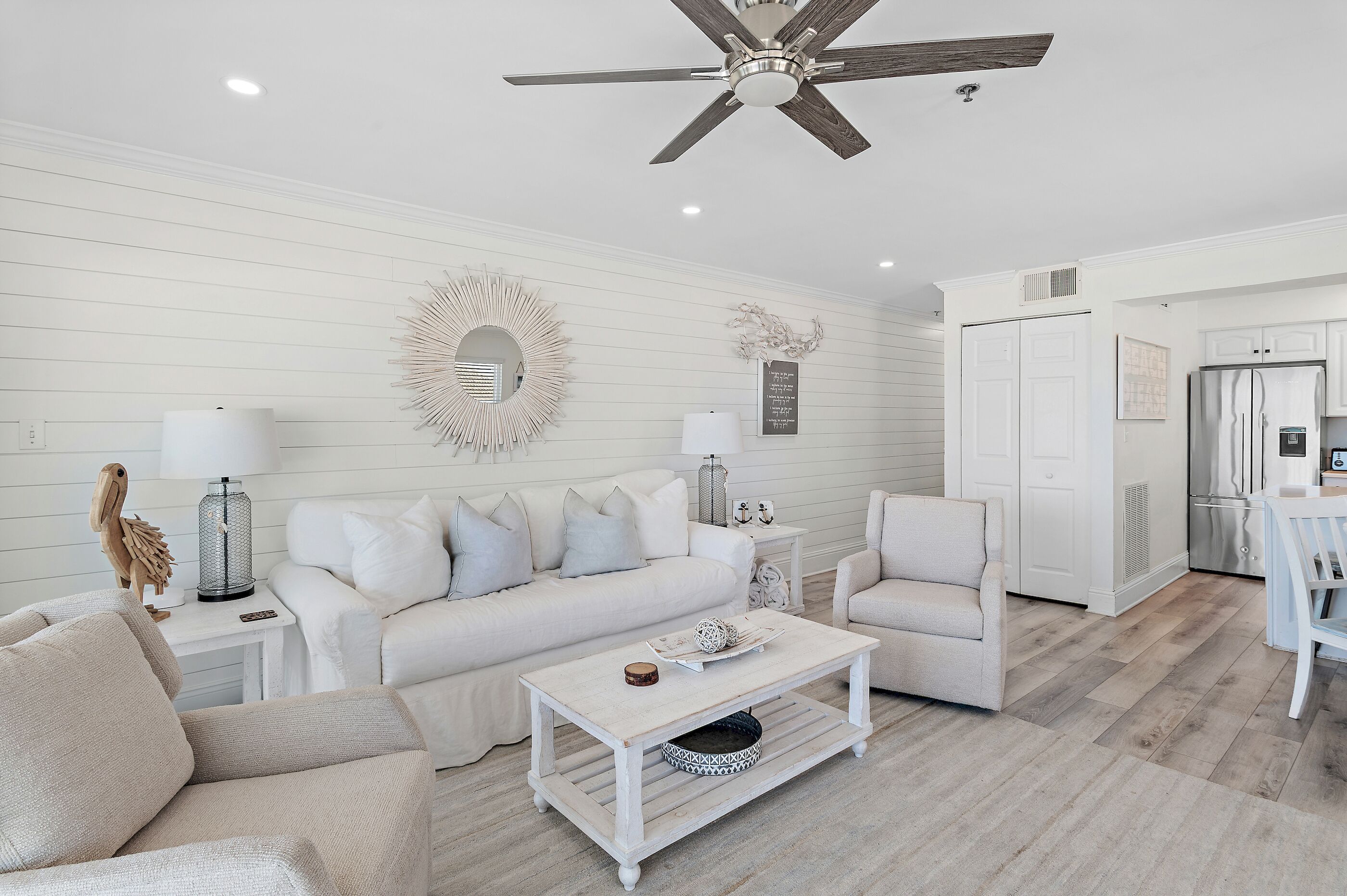 A modern living room with a white sofa, a coffee table, and a ceiling fan.