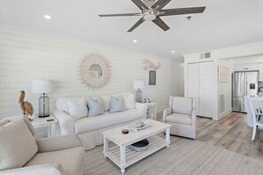 A modern living room with a white sofa, a coffee table, and a ceiling fan. - Gulf Front Corner Unit - Seagrove Beach - Community Pool (Santa Rosa Beach)