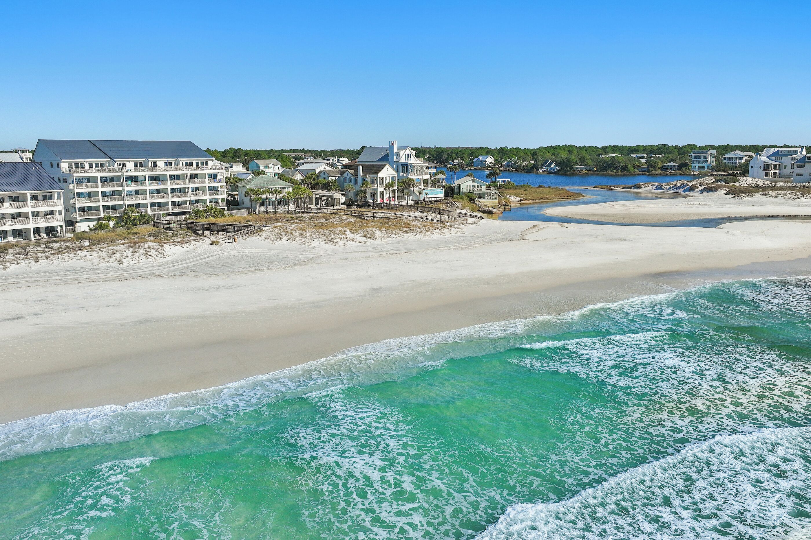 Un hôtel en bord de mer composé de plusieurs bâtiments, doté d’une plage de sable et offrant une vue dégagée sur l’océan.