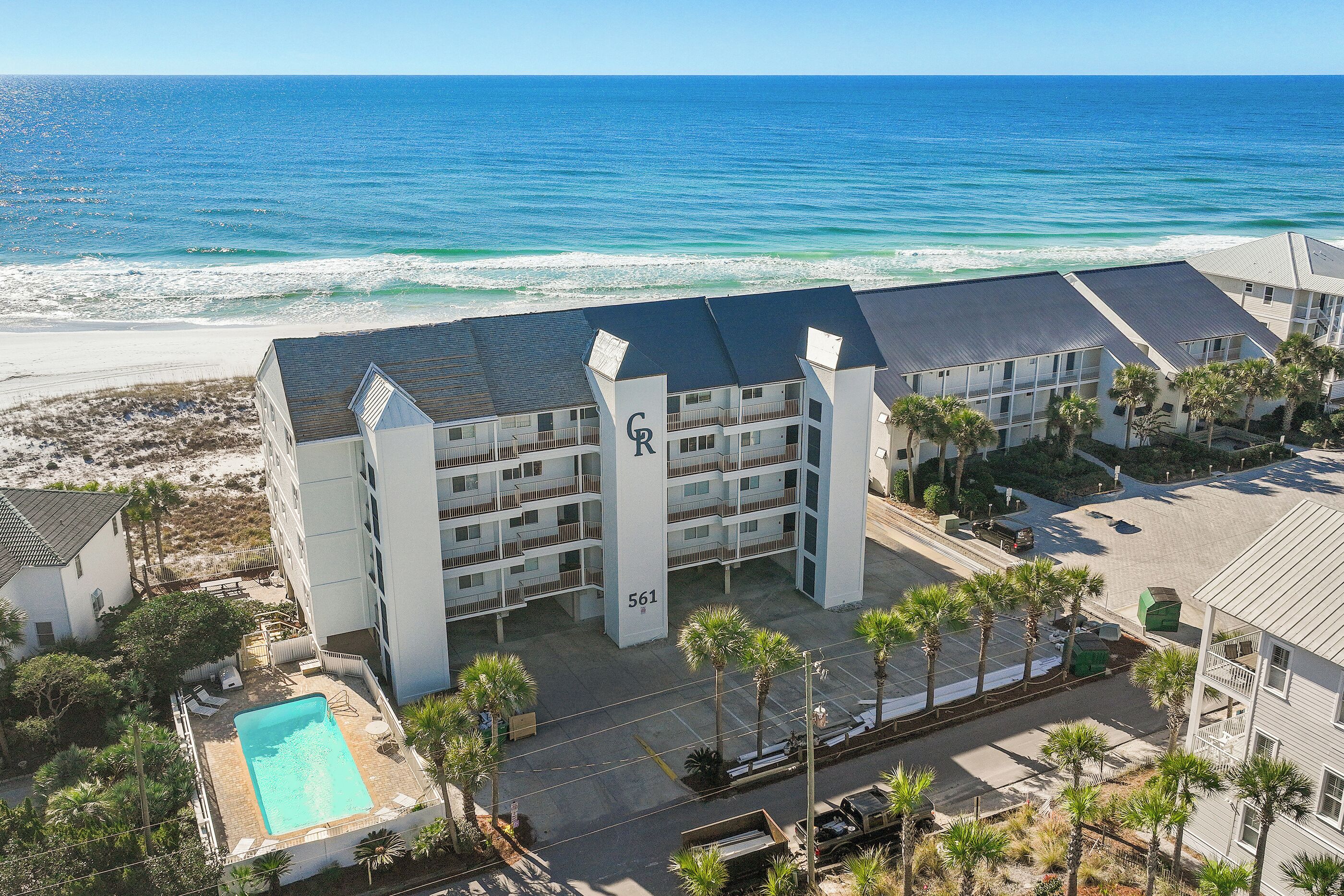 Een meerlaags hotel met een zwembad, gelegen nabij een strand met uitzicht op de oceaan.