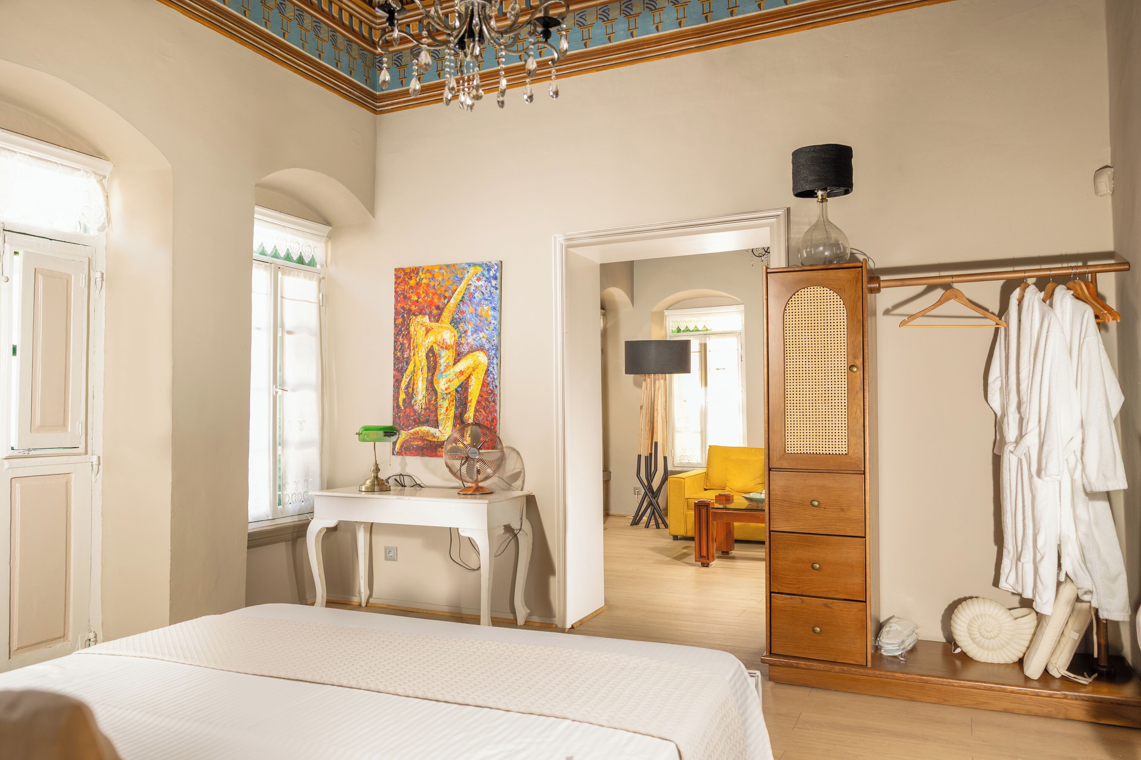 Un dormitorio con cama, escritorio, cuadro, armario y espejo.