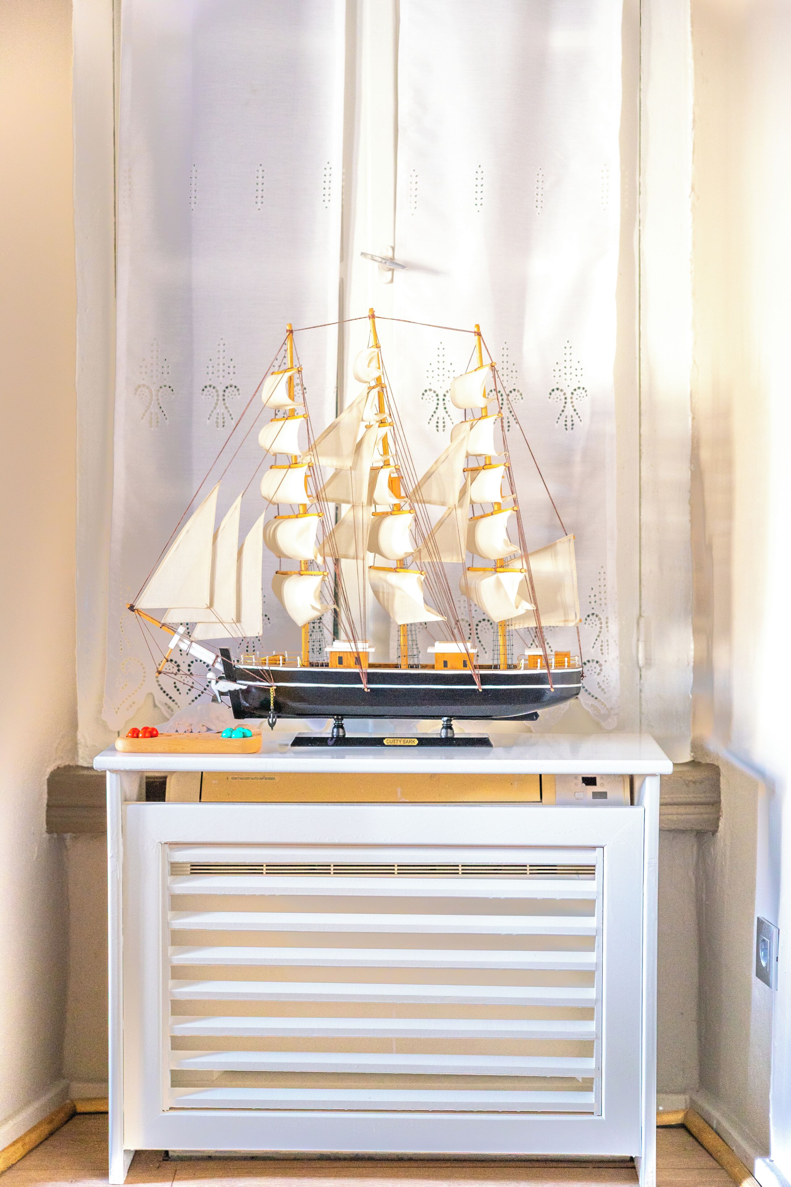 A model ship on a white table with a window in the background.