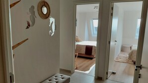A modern bedroom with a large bed, a bench, and decorative wall art. - Luxury Apartment With Pool & Parking (Nieuwpoort)
