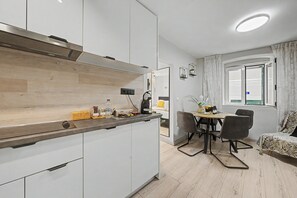 Una cocina moderna con armarios blancos, una encimera de madera y un comedor con mesa y sillas.