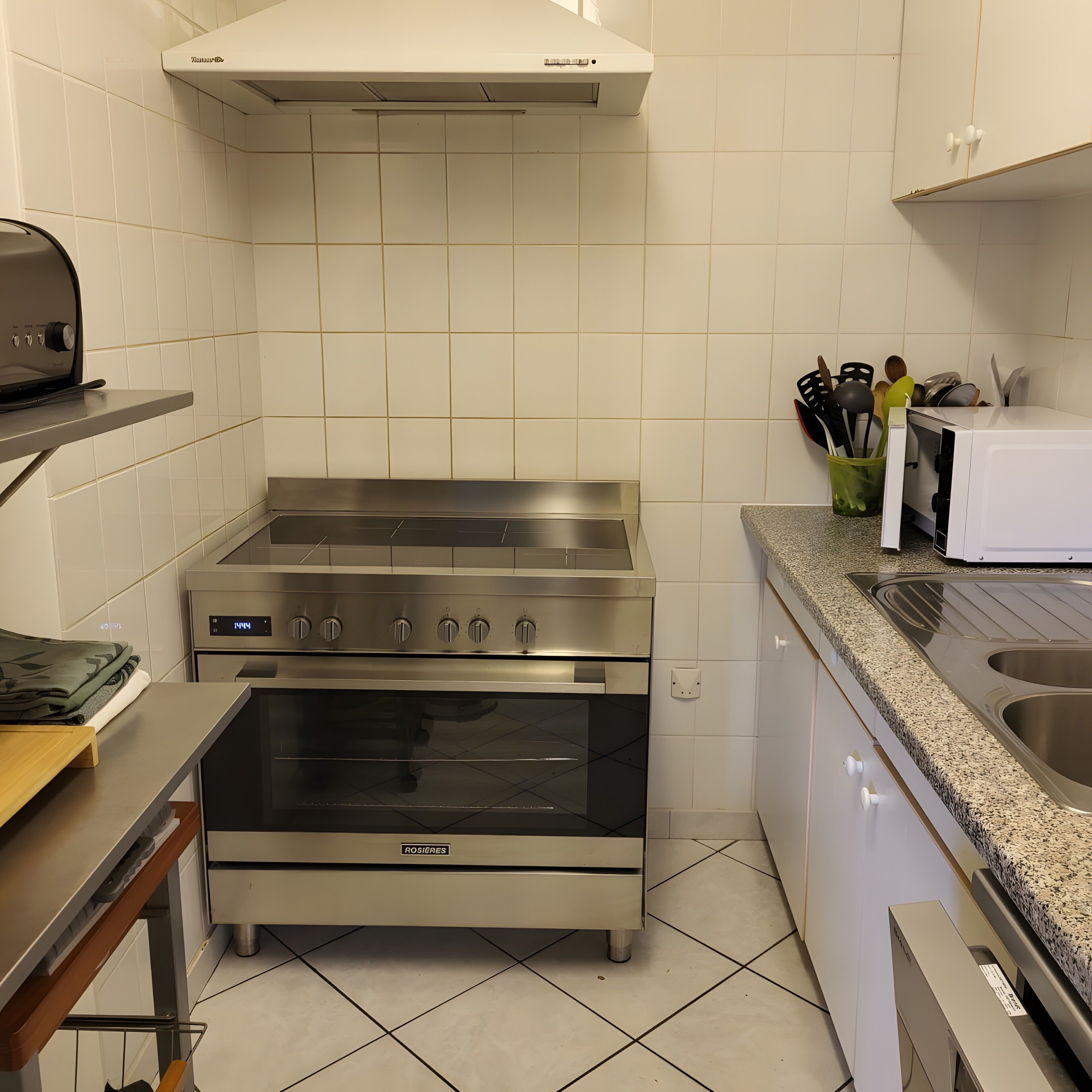 Una cucina con piano cottura, forno e microonde in acciaio inossidabile.