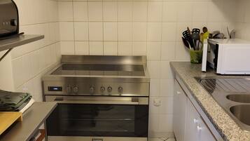Una cucina con piano cottura, forno e microonde in acciaio inossidabile.