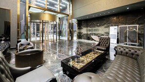 Un'ampia hall dall'arredamento moderno, con un'area salotto centrale che include un tavolino in vetro, comodi divani e un elemento decorativo.
