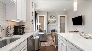 A modern kitchen with white cabinetry, a coffee maker, and a stainless steel dishwasher. - Skyline Haven #1–Nashville Views  –Sleeps 6 (Nashville)