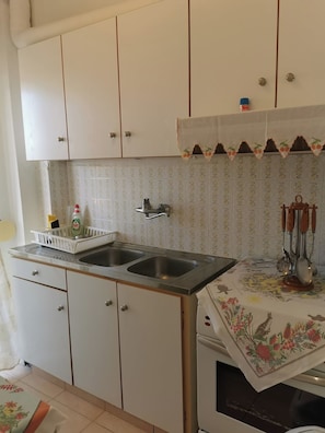 A kitchen with a double sink, white cabinets, a tiled backsplash, and a decorative cloth over the countertop.