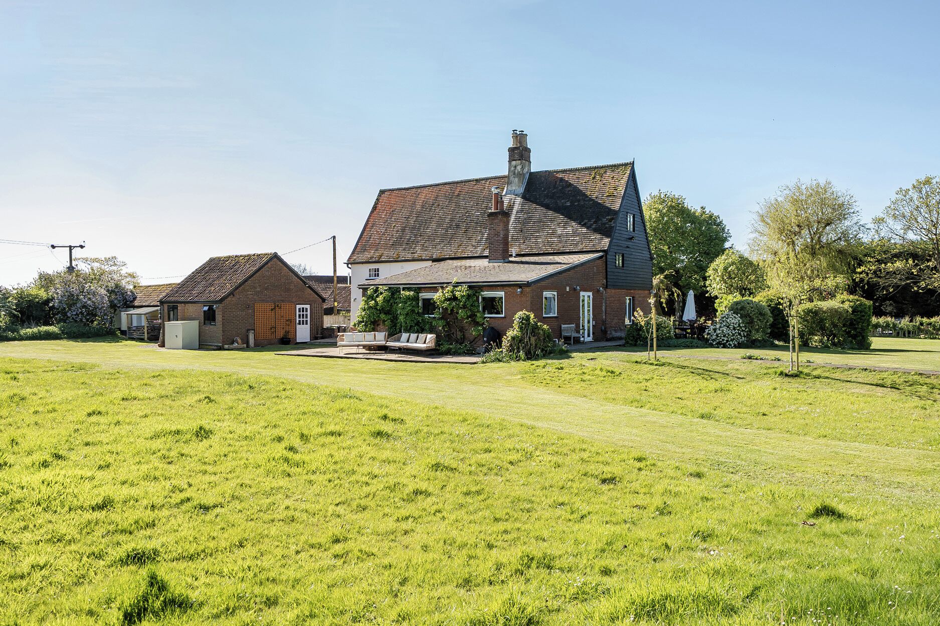 A large house with a spacious lawn, a smaller attached building, and a well-maintained garden.