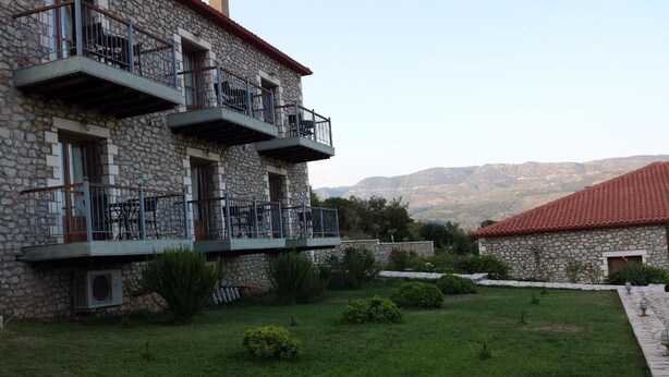 Ein Steinhaus mit Balkon, einem kleinen Garten und Blick auf die Berge.