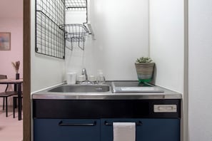 Eine kleine Küche mit Spüle, Wasserhahn und Arbeitsplatte.