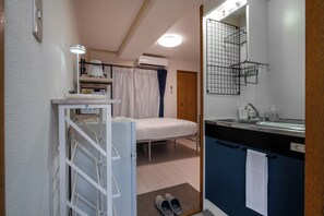 Ein gemütliches Schlafzimmer mit Bett, Nachttisch und kleinem Fenster mit Vorhängen.
