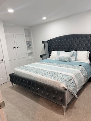 A bedroom with a tufted headboard, a bed with a floral-patterned bedspread, a chest of drawers, and a white wardrobe. - Serene 1-bedroom basement in welcoming Upper Marlboro perfect for getaway (Upper Marlboro)