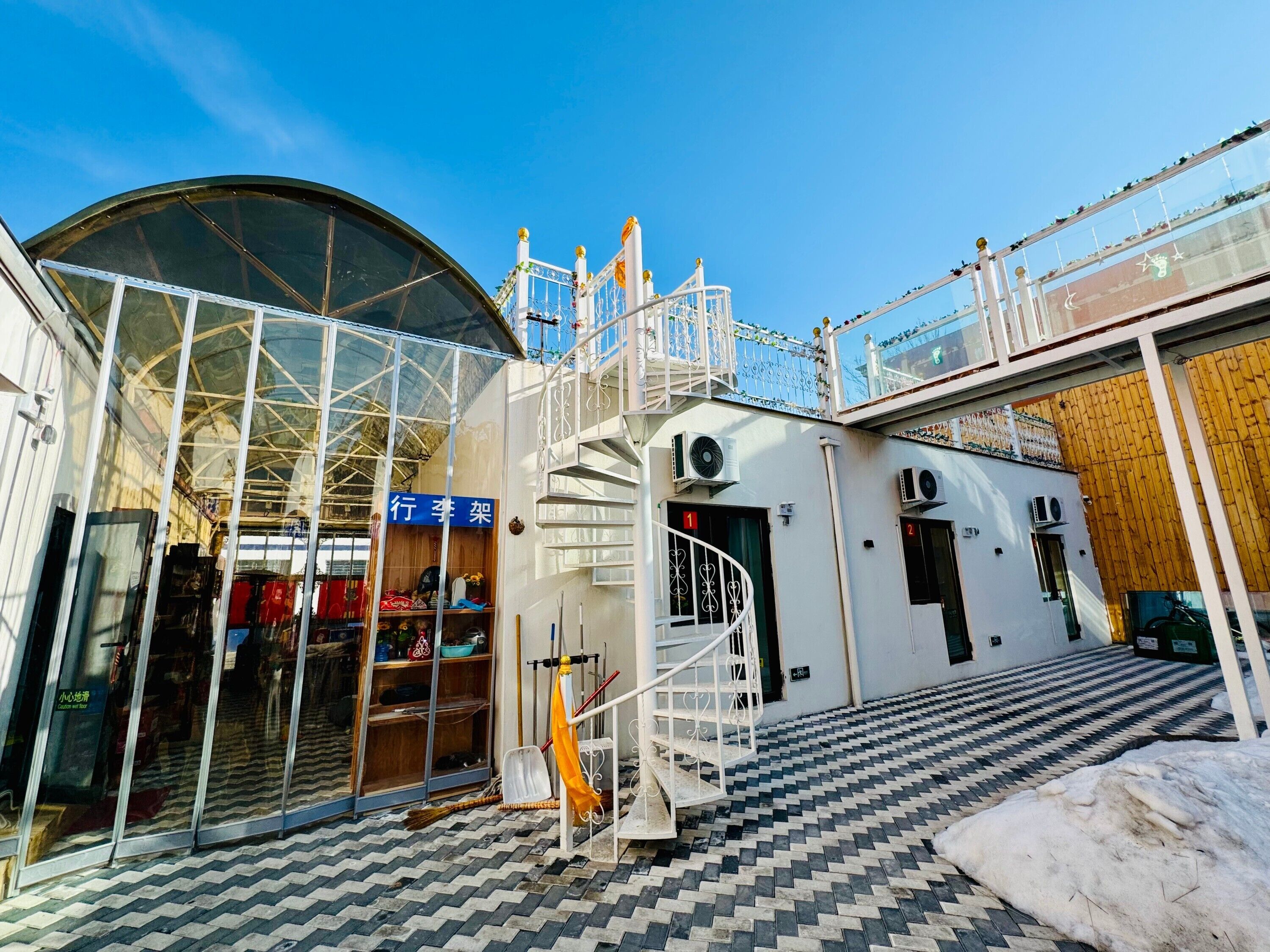 A building with a glass entrance, a spiral staircase, and a tiled floor.