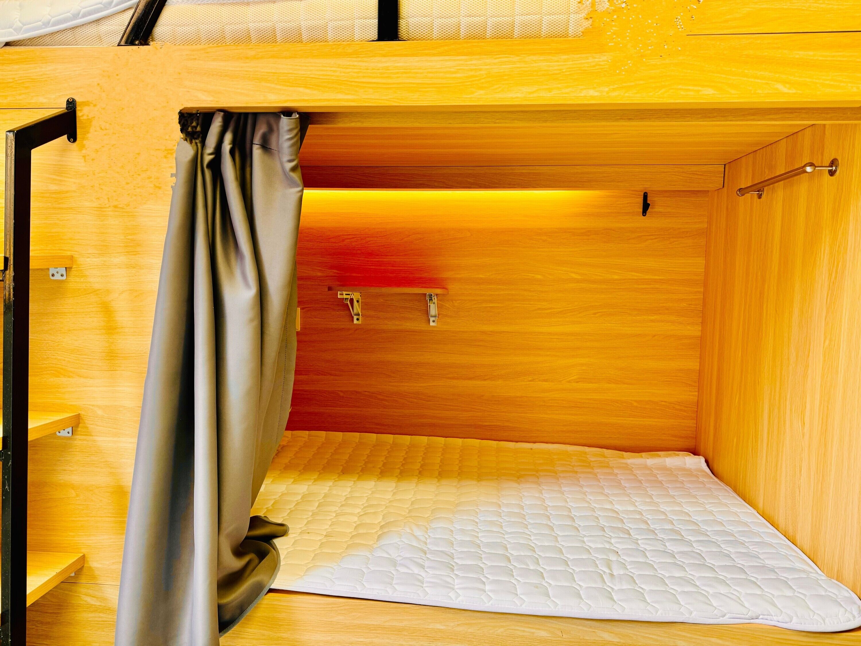 Un petit espace clos, aménagé pour dormir, avec un matelas et un rideau.