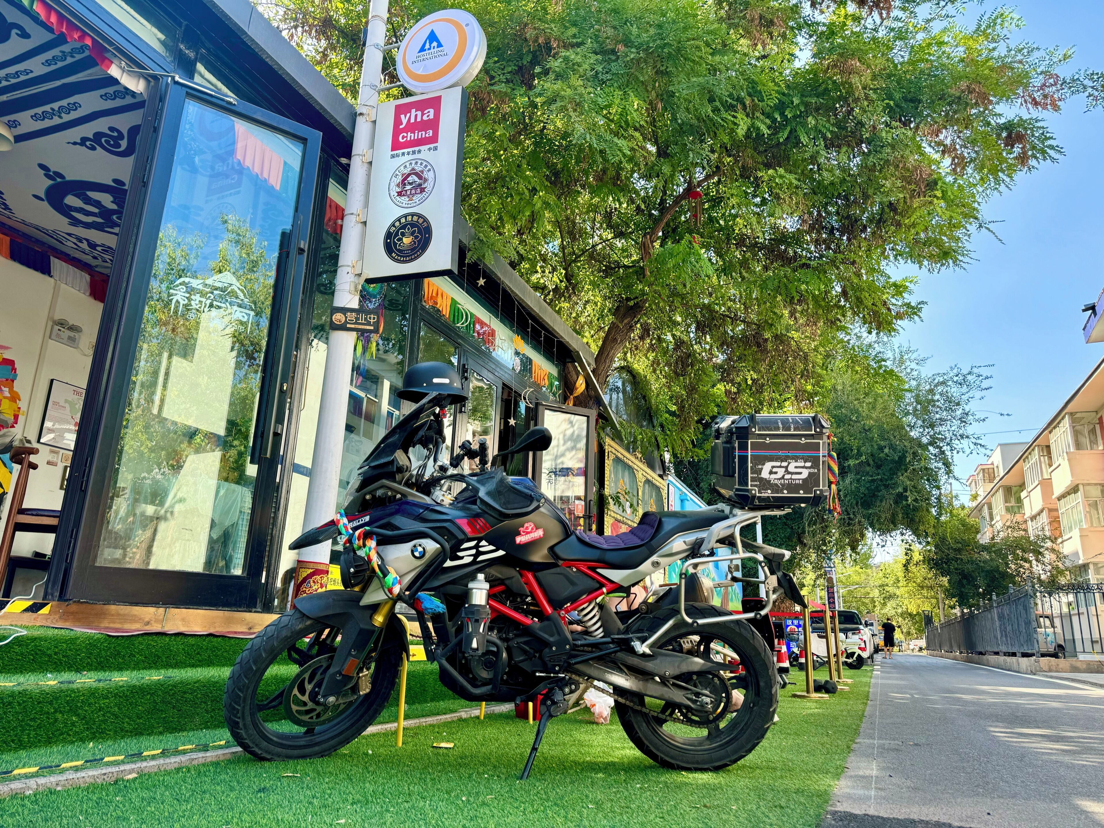 A motorcycle parked on a grassy area in front of a building with signage indicating it is a hostel.