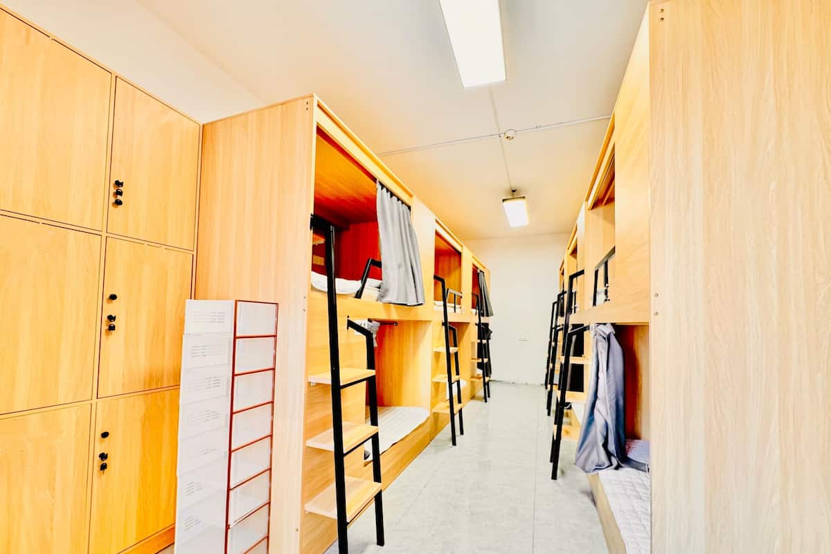 A dormitory room with wooden bunk beds, a ladder, and a whiteboard.