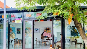 Un caffè con posti a sedere all'aperto, un patio in legno e un albero che offre ombra.