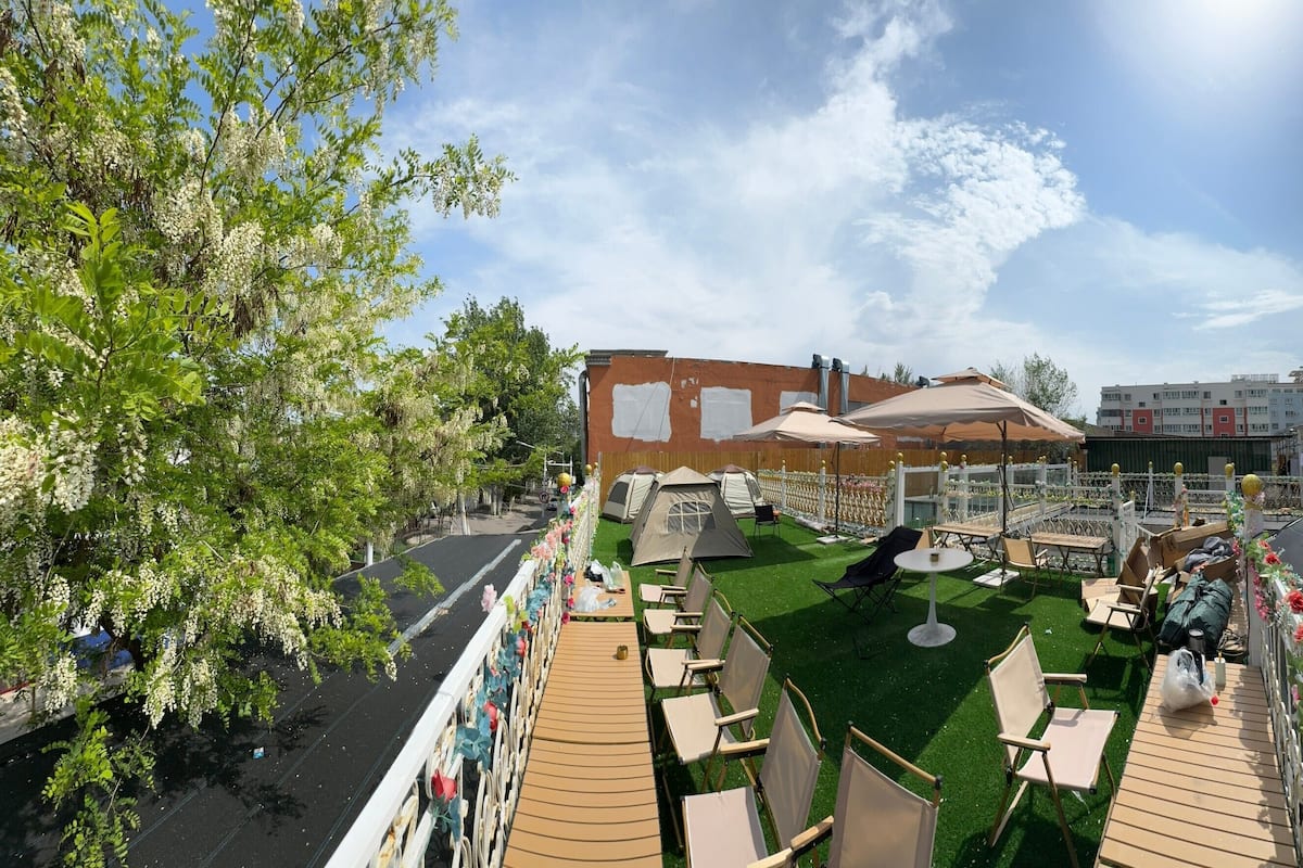 A rooftop terrace with outdoor seating, tents, and a view of the cityscape.