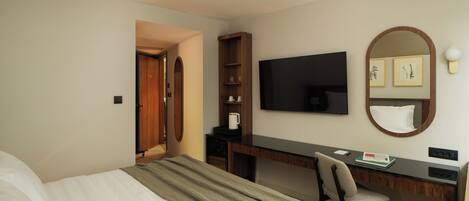 Une chambre d’hôtel équipée d’un lit, d’un bureau, d’une chaise, d’une télévision, d’un miroir et d’une armoire.