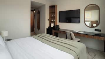 Una habitación de hotel con una cama, un escritorio, una silla, un televisor y un espejo.
