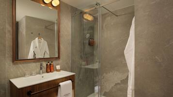A modern bathroom with a glass shower enclosure, a wooden vanity, and a large mirror.