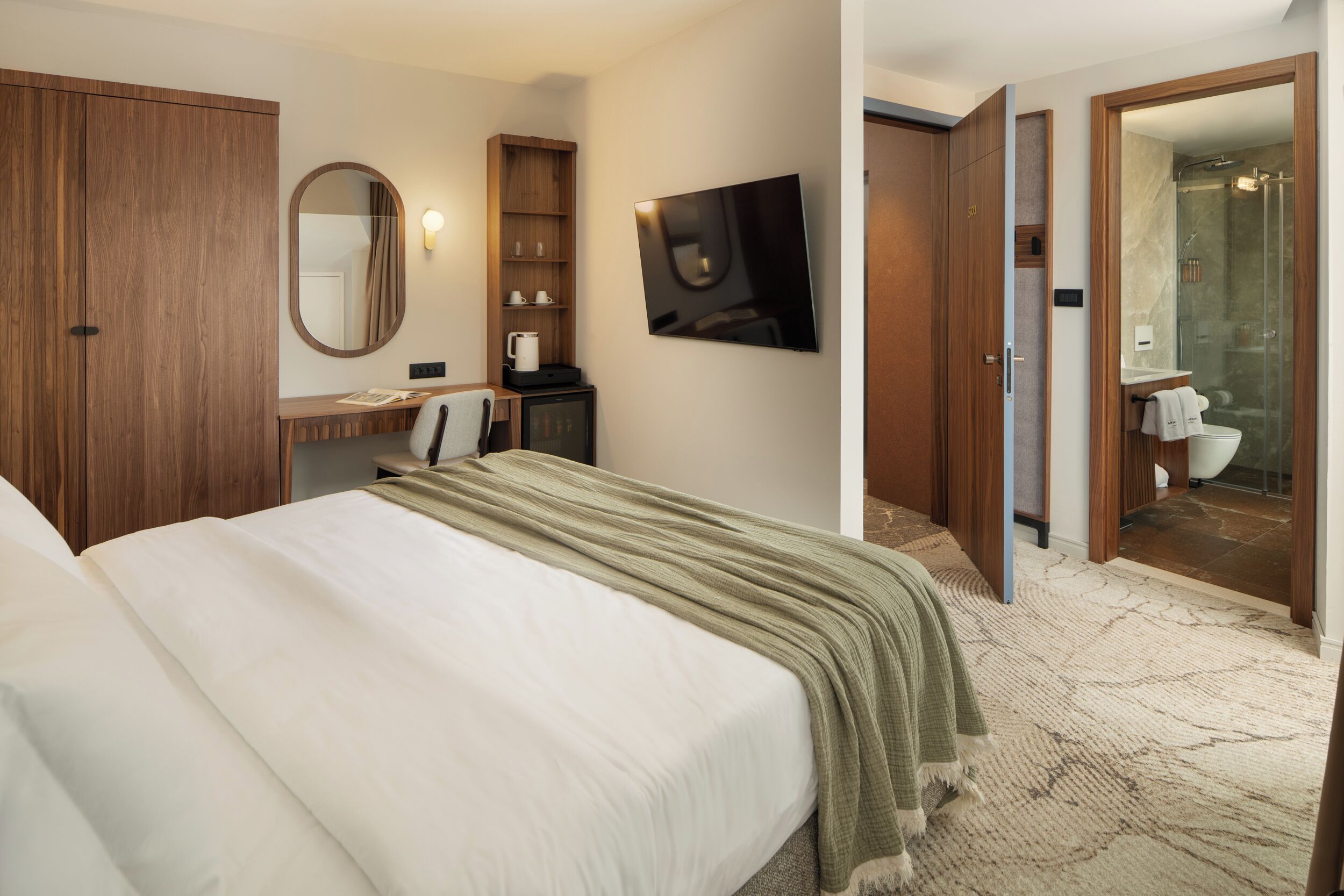 Une chambre d’hôtel comprenant un lit, un bureau avec un miroir, une télévision et une salle de bain avec douche.