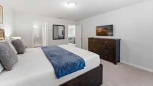 A bedroom with a large bed, a dresser, a mirror, and a painting on the wall. - 5BR Home with Pool & Resort Amenities Near Disney (Davenport)