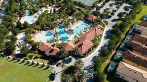 An aerial view of a resort with multiple swimming pools, a tennis court, and a well-maintained landscape with palm trees. - 5BR Home with Pool & Resort Amenities Near Disney (Davenport)