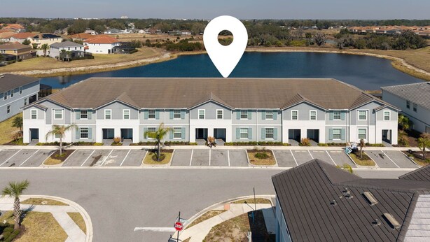 A multi-story building with a parking lot in front, a stop sign, and a large body of water in the background. - 5BR Home with Pool & Resort Amenities Near Disney (Davenport)