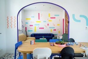 A room with a wooden table, blue chairs, a blue sofa, and a brick wall. - Cool Cool House (Liège)