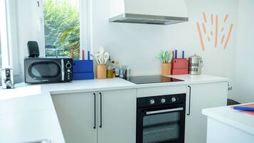 Une cuisine moderne équipée d’un four à micro-ondes, d’une cuisinière et d’un four. Une fenêtre offre une vue sur la verdure environnante.