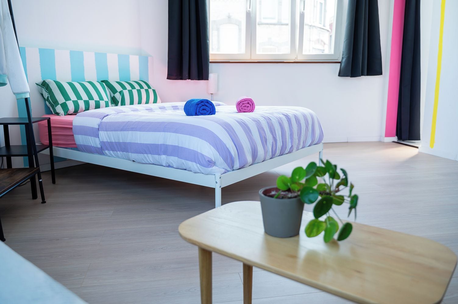 Une chambre à coucher moderne avec un lit, une petite table et une plante en pot.