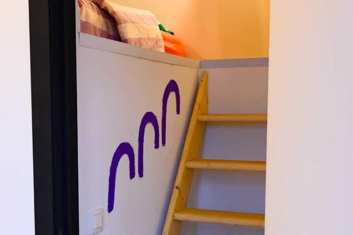 A staircase with a wooden handrail and a wall with purple graffiti.