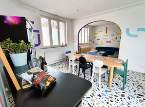 A room with a dining table, chairs, a sofa, a window, and a radiator. - Cool Cool House (Liège)