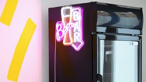 A modern kitchen with a neon sign, a glass cabinet, and wooden stools. - Cool Cool House (Liège)