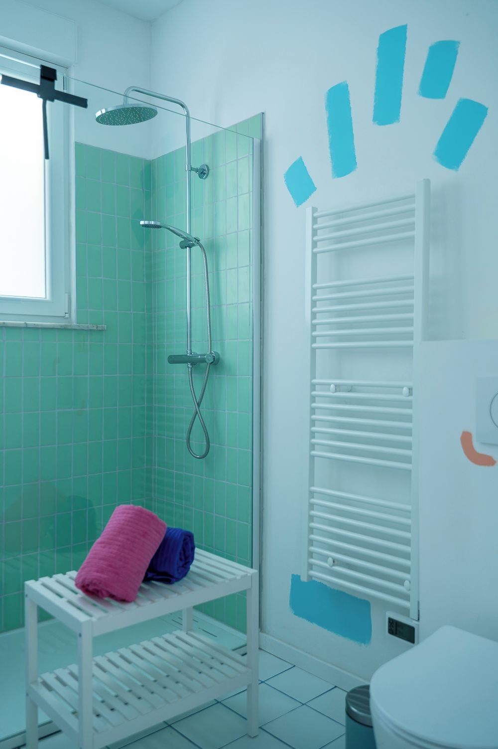 Een badkamer met een douche, toilet en handdoekhouder.