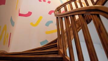 A wooden staircase with a handrail and a wall with abstract shapes.