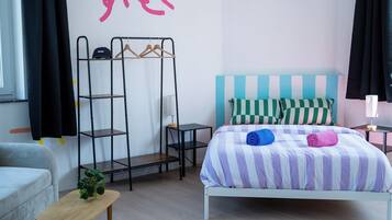 Een slaapkamer met een bed, een metalen schapunit, een kleine tafel en een raam.