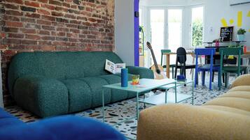 Un salon chaleureux avec un canapé vert, une table basse et un coin repas comprenant des chaises et une table.