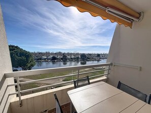 Een balkon met uitzicht op een rivier en verre gebouwen.